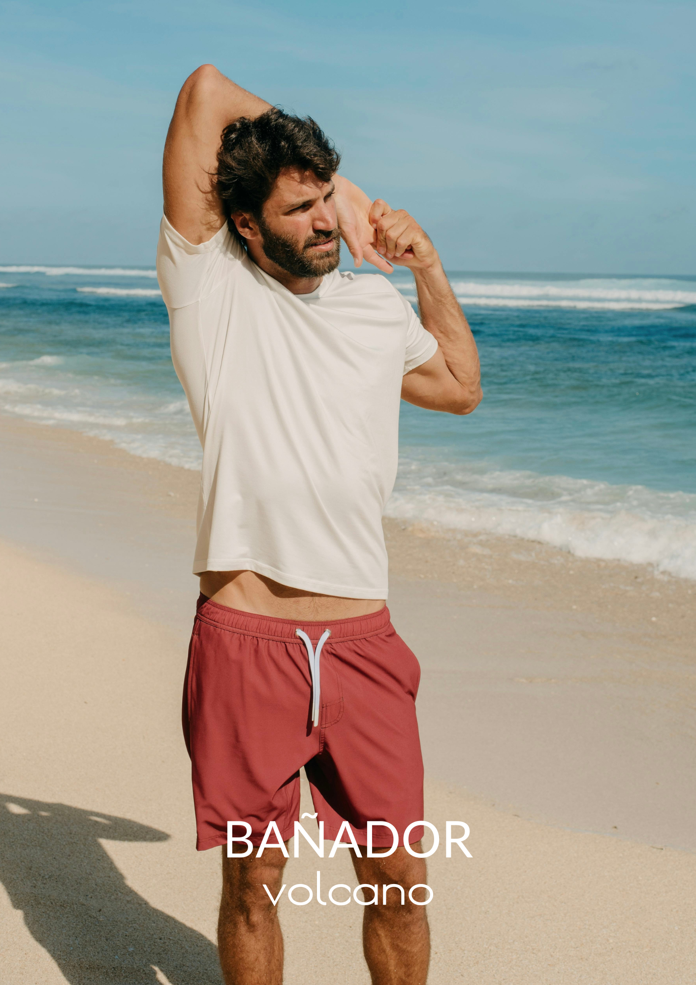 hombre en la playa con bañador granate de kou y camiseta blanca