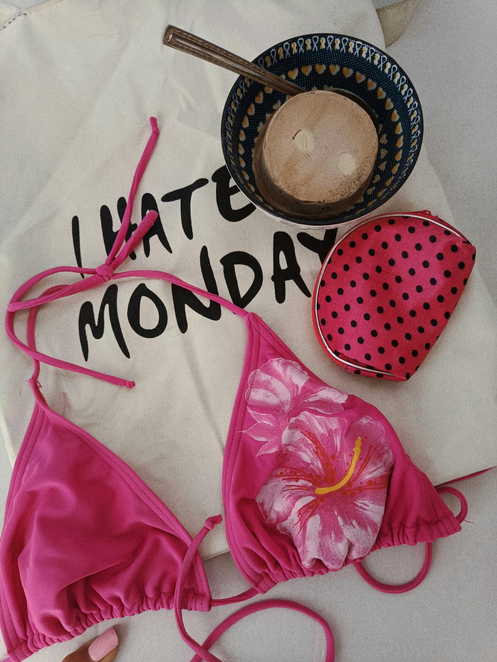 bikini en tendencia con estampado de flor de color rosa, apoyado sobre una bolsa de I hate monday que es tendencia