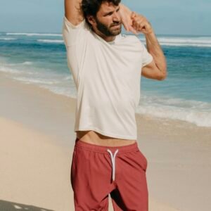 hombre en la playa con bañador volcano de kou y camiseta blanca